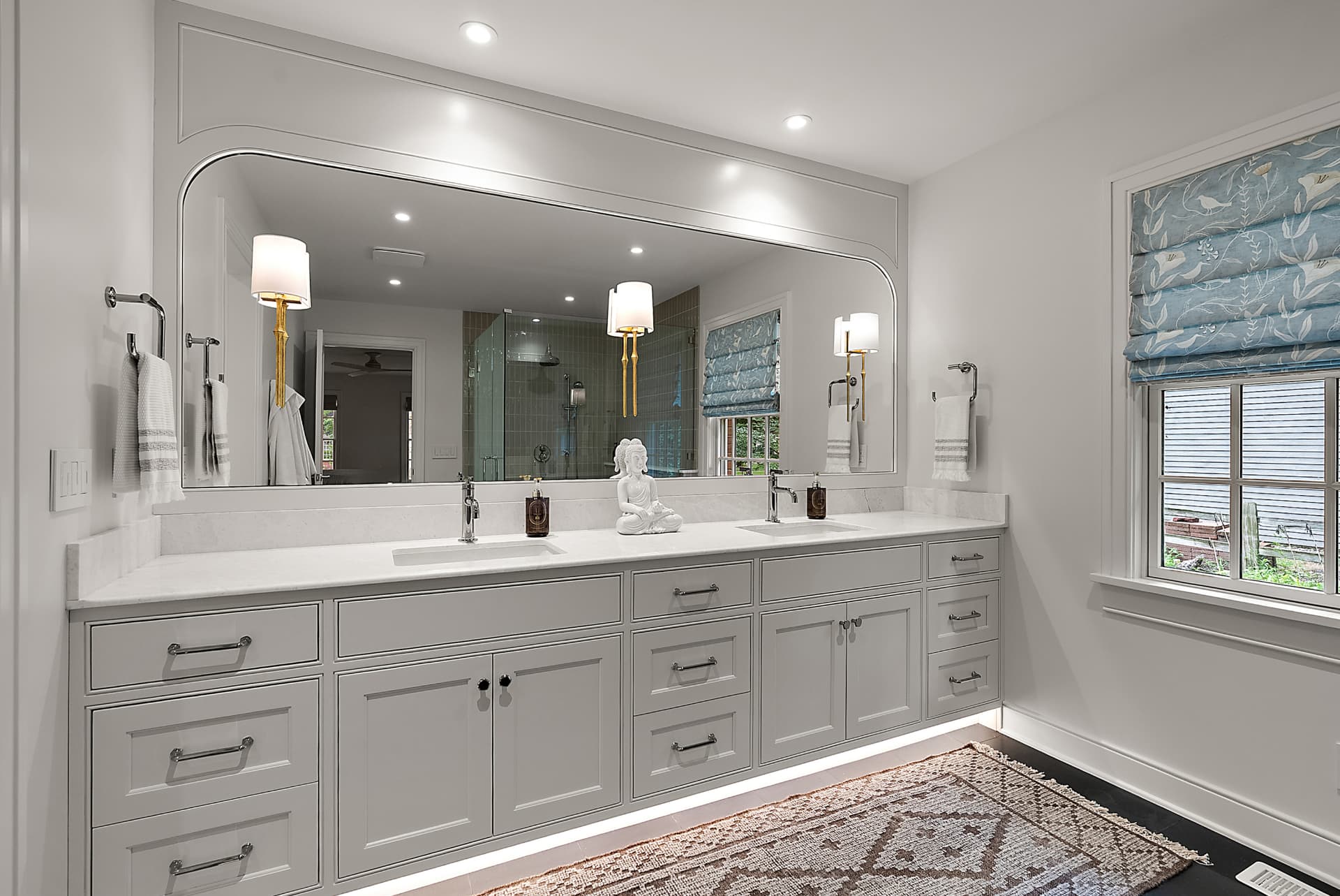 Custom bathroom vanity with a long painted cabinet run and framed mirror
