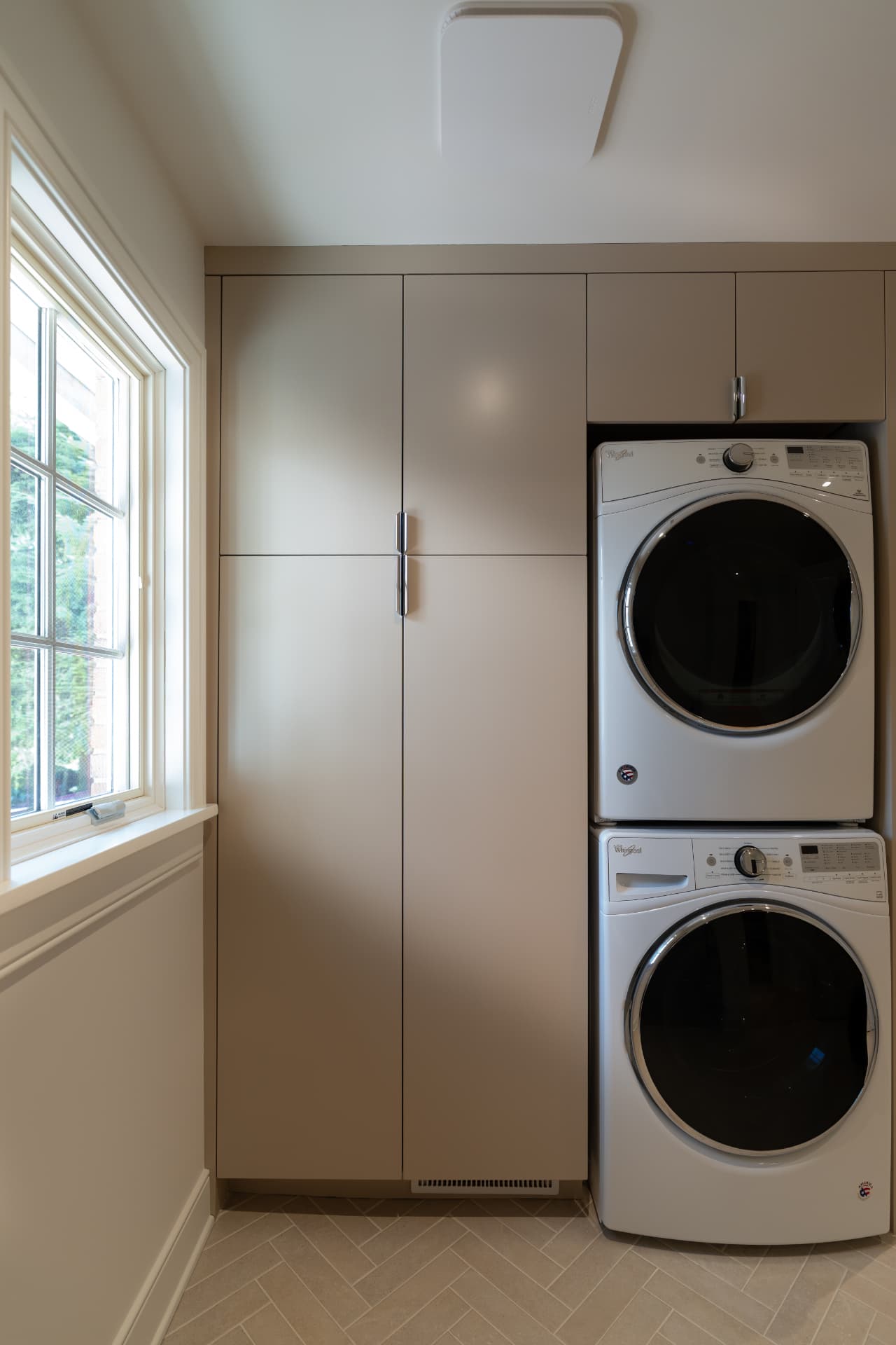 Custom laundry room cabinetry with tall storage and stacked washer and dryer